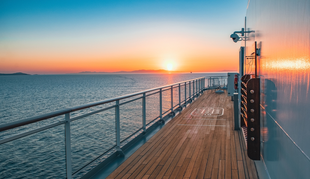 Golden sunset viewed from a cruise ship's open teak deck over calm ocean waters