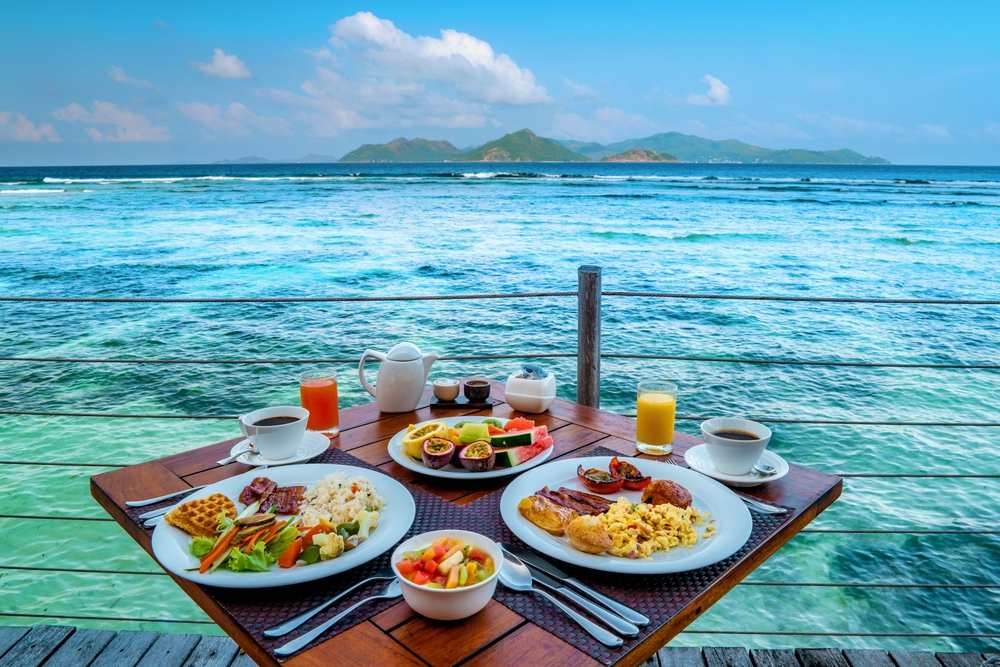 Tropical breakfast spread for two on an overwater deck with turquoise Caribbean sea views